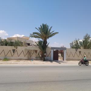 a person riding a motorcycle down the street at Résidence Kyranis Chambre Hannon in Sfax +2 photos