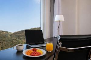 a desk with a laptop and a plate of fruit at Fiesta Inn Express Puebla Finsa in Puebla