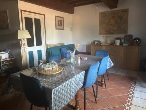 a dining room with a table and blue chairs at La maison bleue de Béa in Musigny