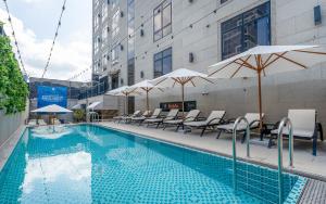 a swimming pool with chairs and umbrellas next to a building at 대구 2월 호텔 동성로점 in Daegu