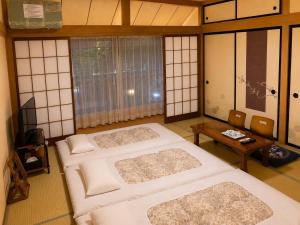 a room with three beds and a table at Yamanaka Lake Ryozan in Yamanakako