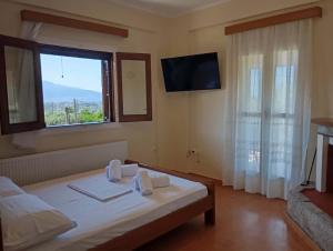 a bedroom with a bed with a window and a television at villa vitta - bellissimo villagio in Kastrákion