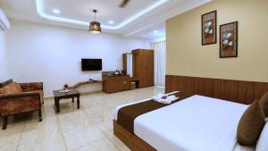 a hotel room with a bed and a chair and a television at Red Tullip Md Valley Resort & Spa - Luxury Resort With Swimming Pool, Udaipur in Udaipur