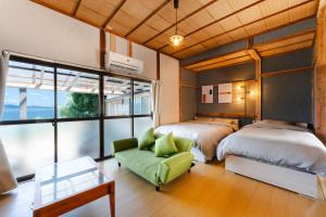 a bedroom with two beds and a green couch at Azure Kawatana in Mitsugoe