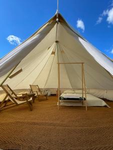a tent with two chairs and a bed in it at Aluna Camp in Nudo