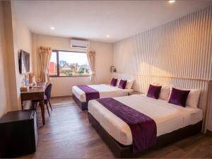 a hotel room with two beds and a desk at Excel Hotel Bangkok former Sri Krungthep Hotel in Bangkok
