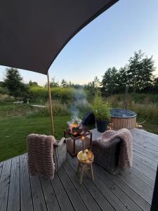 a wooden deck with two chairs and a fire pit at Het Kleine Genoegen in Heelweg