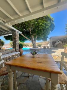 a wooden table on a patio with a tree at Paros Poolside Cozy Nests - Summer & Salty Getaways in Kalami