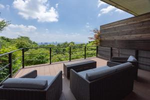 a balcony with chairs and a view of the forest at 山荘 風の杜 Sanso Kazenomori in Minoo