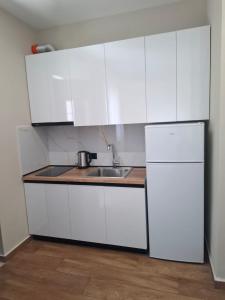 a white kitchen with a sink and a refrigerator at Vila Familjare Vlore in Vlorë +4 photos