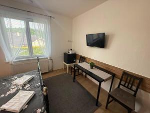 a living room with a table and a tv on the wall at Penzion V Hájku in Vřesina