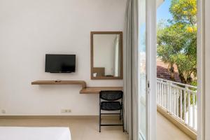 a room with a mirror and a television and a balcony at Townhouse Oak The Vinhill Studio in Bangli