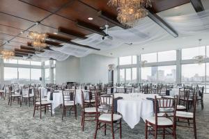a banquet room with white tables and chairs and windows at The Strathallan Rochester Hotel & Spa, Tapestry by Hilton in Rochester