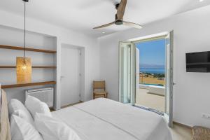 a white bedroom with a bed and a sliding glass door at Asana Villas by Raise in Márpissa +98 photos
