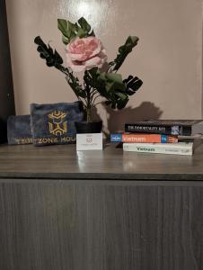 a flower in a vase on a table with books at Tzone's Hostel - Quiet Place in Ho Chi Minh City