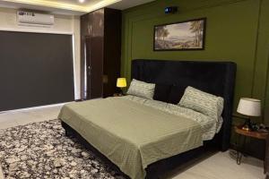 a bedroom with a bed with a green wall at Spacious Apartment by Urban Residence in Multan