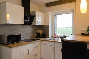 a kitchen with white cabinets and a sink and a window at Bingers kleine Scheune in Willich