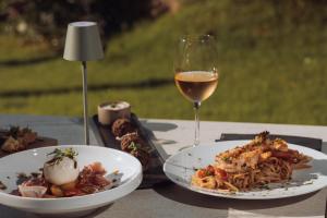 a table with two plates of food and a glass of wine at New Beach Hotel in Planos