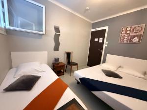 a bedroom with two beds and a window at Hotel le Bon Soleil in Les Sables-d'Olonne