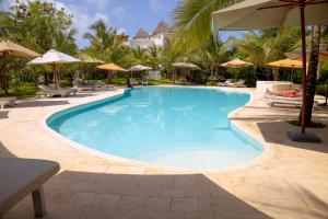 a swimming pool with chairs and umbrellas at a resort at Villa Zuri at Papa Remo in Watamu
