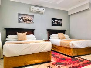 two beds in a hotel room with two beds at Radiant Resort in Manzini +19 photos