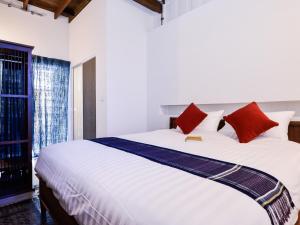 a bedroom with a large white bed with red pillows at Neighbor Phuthon in Bangkok +56 photos