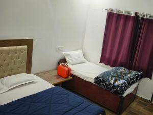 a small room with two beds and a window at shiv shankar resort and hotel in Phata