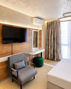 a bedroom with a bed and a chair and a tv at Oryn Suites in Tirana