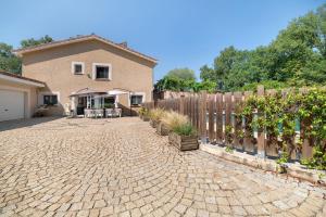 a house with a fence and a brick driveway at Appartement Type F4 in Maurens