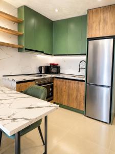 a kitchen with green cabinets and a stainless steel refrigerator at Oryn Suites in Tirana