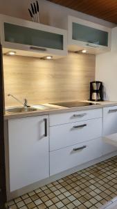 a kitchen with white cabinets and a sink at Ferienhaus Bambach in Fladungen