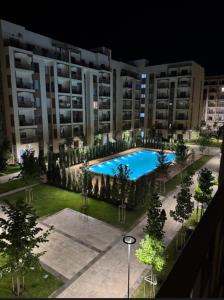 an apartment complex with a large swimming pool at night at Чарвак Дарвозаси in Chorwoq +15 photos