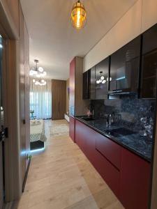 a large kitchen with black counter tops and red cabinets at Чарвак Дарвозаси in Chorwoq