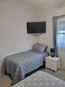 a bedroom with a bed and a flat screen tv at Backpackers Homestay 21-36 yrs ONLY in Caloundra