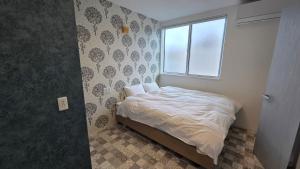 a small bedroom with a bed and a window at ガジュマル House in Tonosho