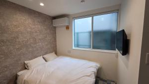 a small bedroom with a bed and a window at ガジュマル House in Tonosho