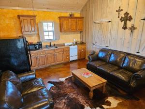 a living room with a leather couch and a table at Breezy Hills Cottages - Moonlight Cottage in Fredericksburg