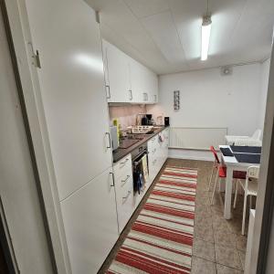 a kitchen with white cabinets and a table and a kitchen rug at Centrala Tanumshede in Tanumshede