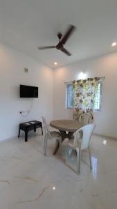 a dining room with a table and chairs and a ceiling fan at Dreamy beach villa in Pondicherry