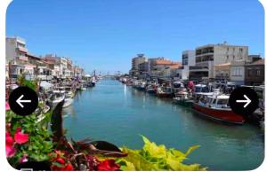 a river with boats in a city with buildings at Aprile in Palavas-les-Flots