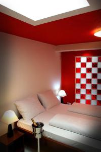 a bedroom with a white bed with a red wall at Hotel Carpymore in Biograd na Moru