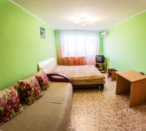 a room with a bed and a couch and a television at Apartment on Sverdlova in Tyumen