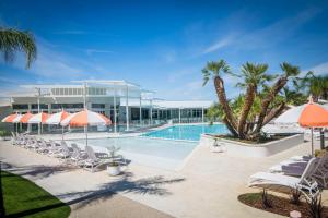 a resort pool with chairs and umbrellas and palm trees at Trentham Waters Resort in Gol Gol