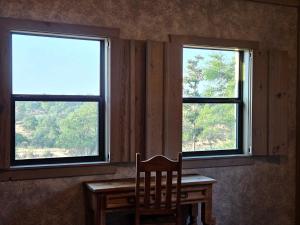 a wooden table with a chair in front of two windows at Breezy Hills Cottages - Moonlight Cottage in Fredericksburg