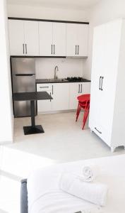 a kitchen with white cabinets and a sink and a red chair at Rajan apartement in Piqeras