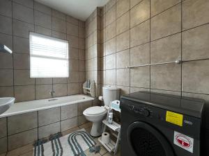 a bathroom with a toilet a sink and a washing machine at La Palma Villa 8 in Mossel Bay +9 photos