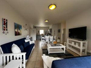 a living room with a blue couch and a tv at La Palma Villa 8 in Mossel Bay