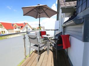 a balcony with a table and an umbrella at Haus Sonne - Whg 08 in Thiessow