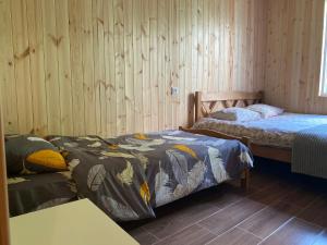 two beds in a room with wooden walls at Zhorzholiani House - Betkili in Lakhiri