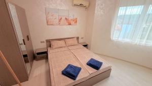 a bedroom with a bed with two blue pillows on it at Moni Sunset Apartment Balchik in Balchik